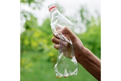 Image Person squeezing empty plastic bottle.